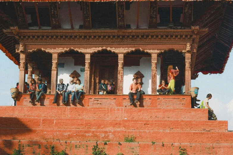 people are hanging out on the top of a red brick building