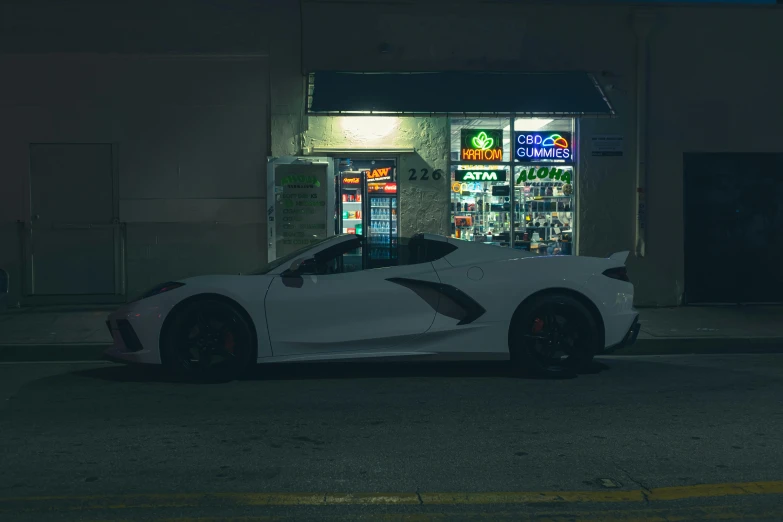 white sports car parked at a convenience store in the dark