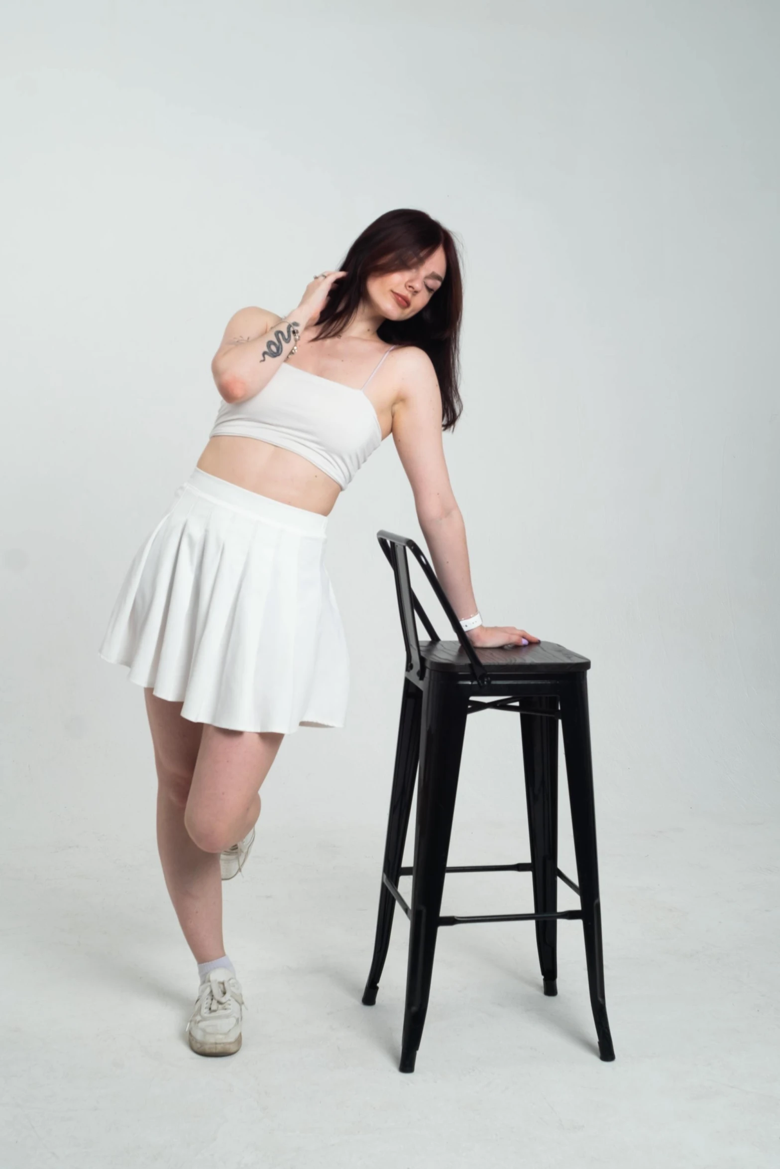 a beautiful young woman standing next to a chair