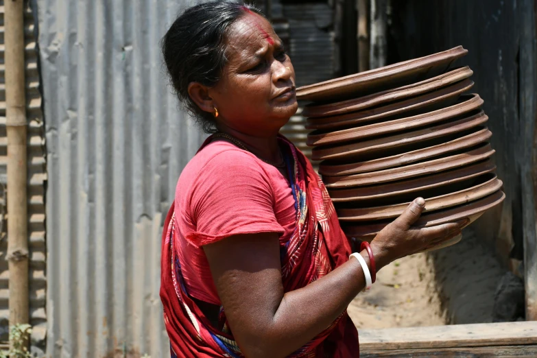 a woman holds large stack of stacked plates in her hands