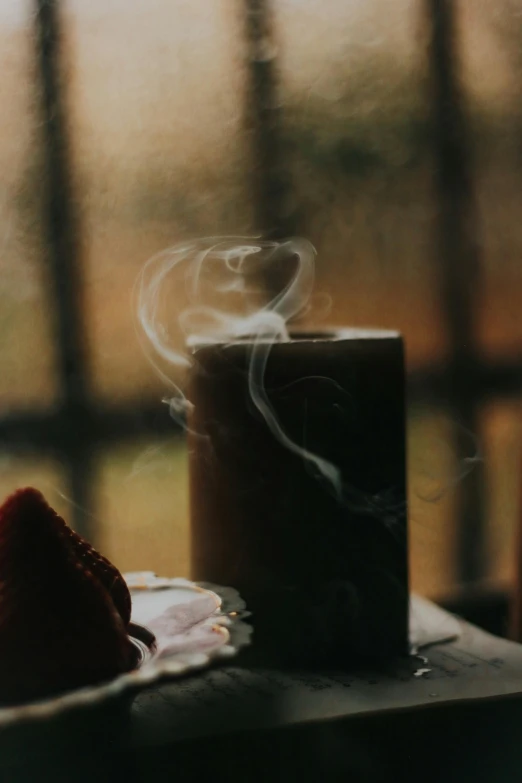a coffee mug with steam coming out sits on a table near a strawberry