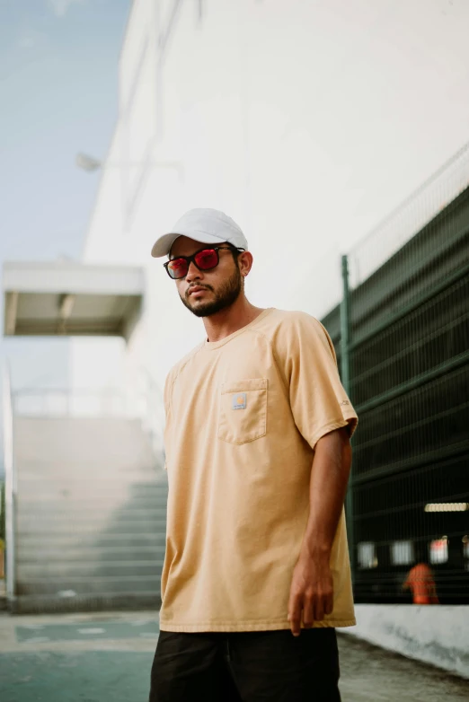 a man wearing sunglasses and a yellow shirt and a white cap