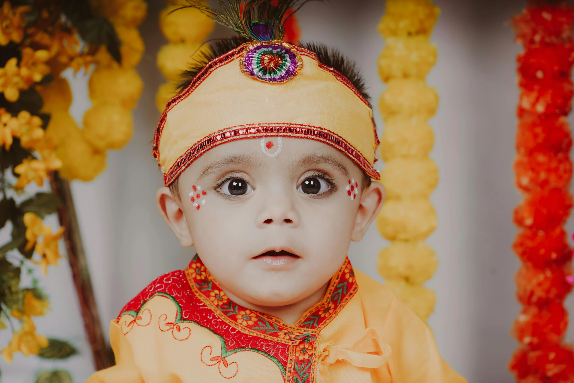 a baby dressed up wearing a yellow outfit and colorful headdress