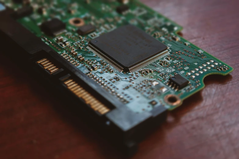 a green and black computer board on a wooden table