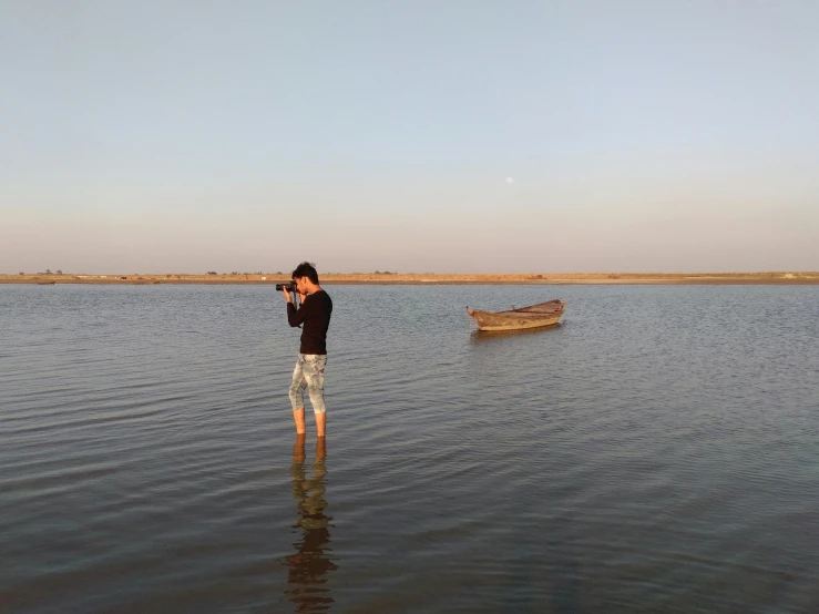 a man standing in water next to boats