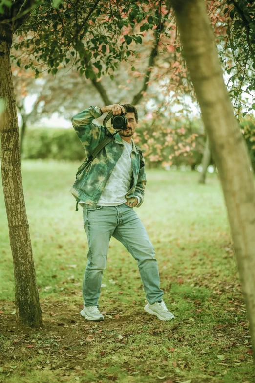 a man wearing jeans and an animal print jacket posing in a park