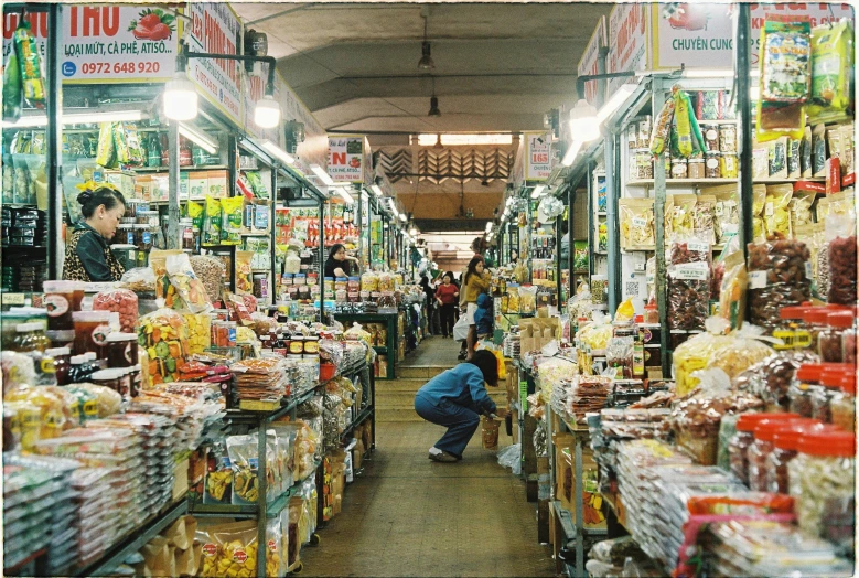 a man kneeling down near piles of items at a market