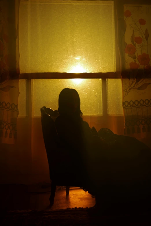 the shadow of a person sitting in a chair by a window