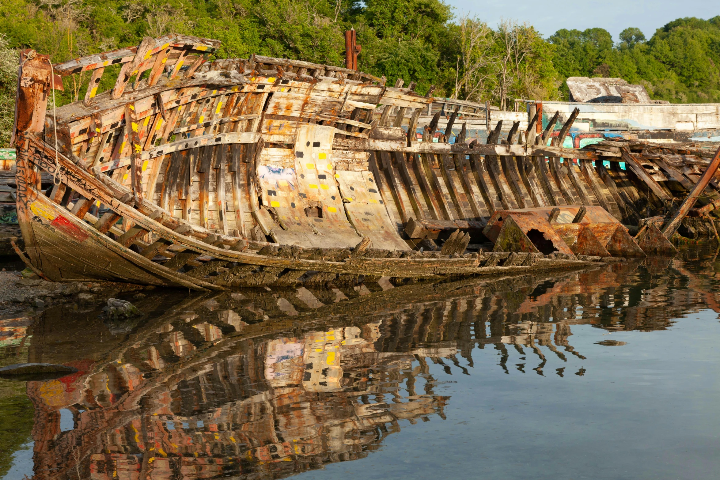 an old rusty boat is sitting still in the water