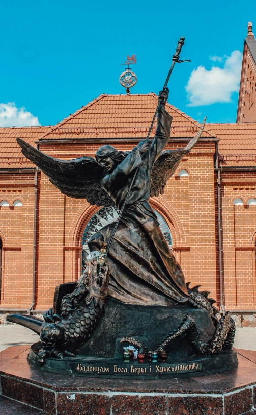 statue with a bird in its beak outside a large brick building