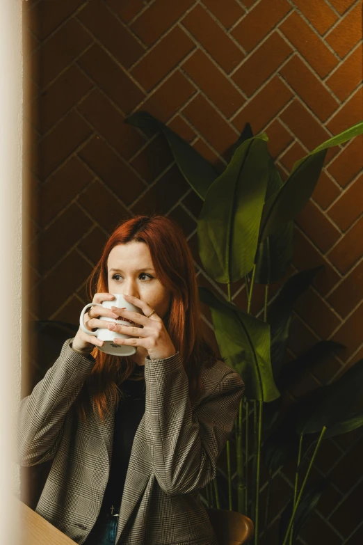 a woman drinking coffee in front of a window