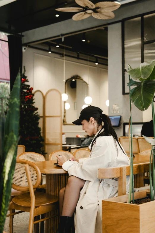 a woman sitting at a table with a plant and laptop