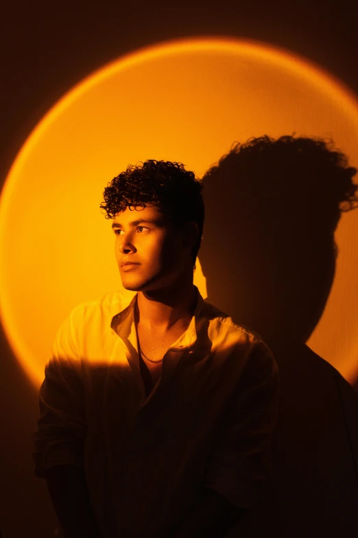 a man standing in front of a light orange circle