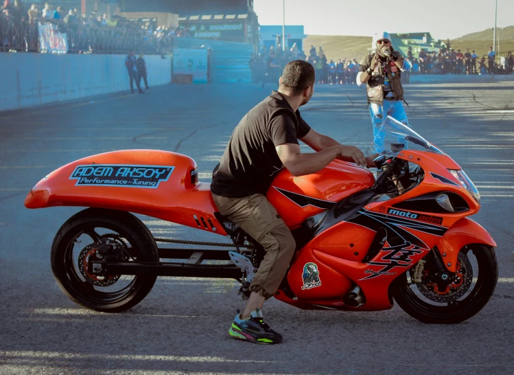 a man sitting on an orange motorcycle as it looks like he is driving around the track