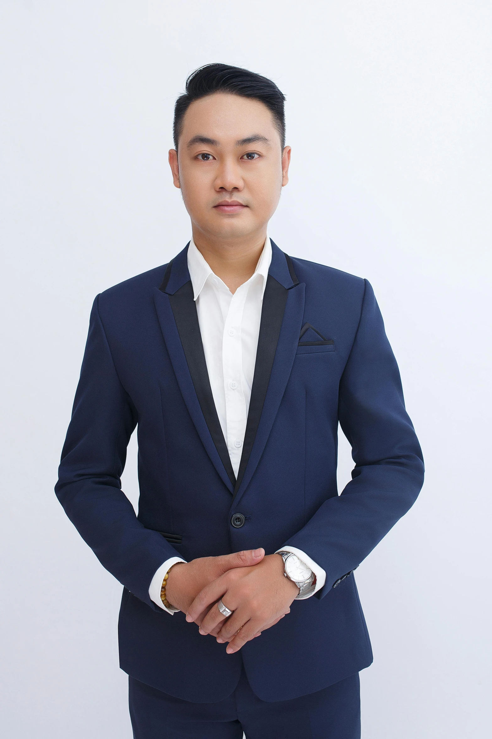 man in suit with black lapel standing in studio