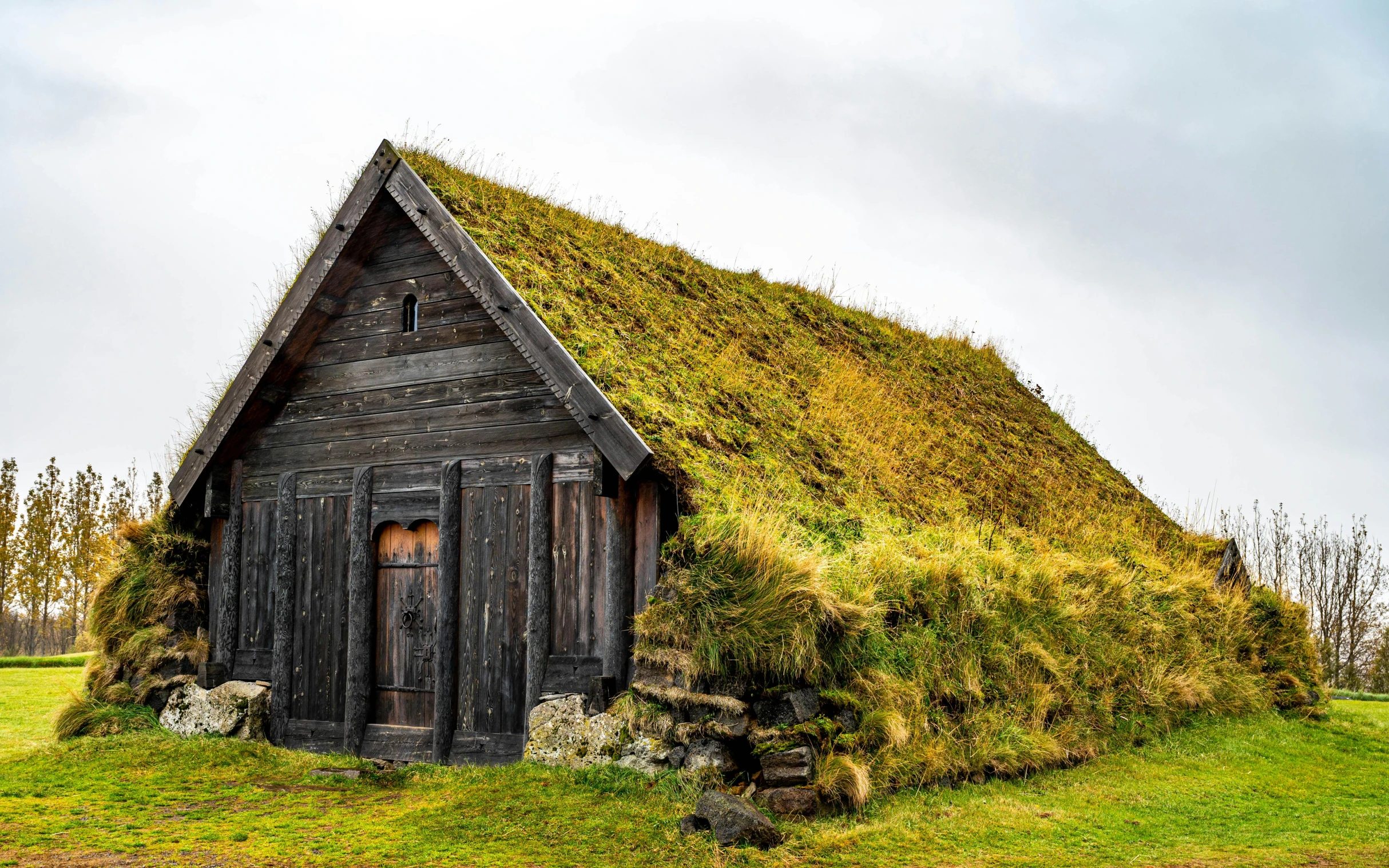 an old wooden hut is adorned with grass