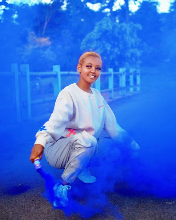 a woman squatting on a ground with blue smoke