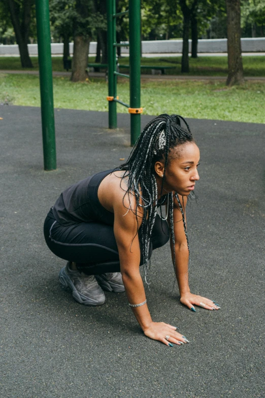 a young woman kneeling on her hands on the ground in the park