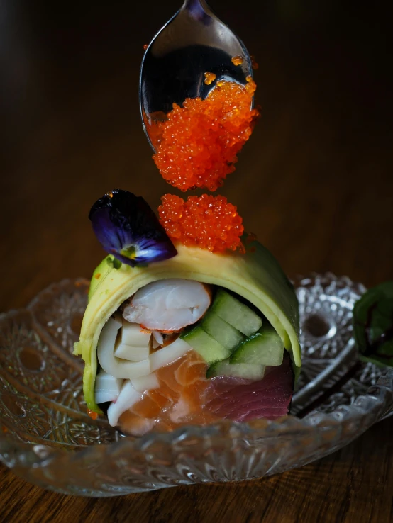 a small sushi dish in a clear bowl with silver spoon