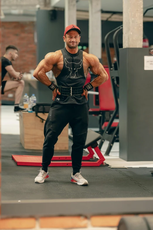 a man is standing in a gym posing for the camera