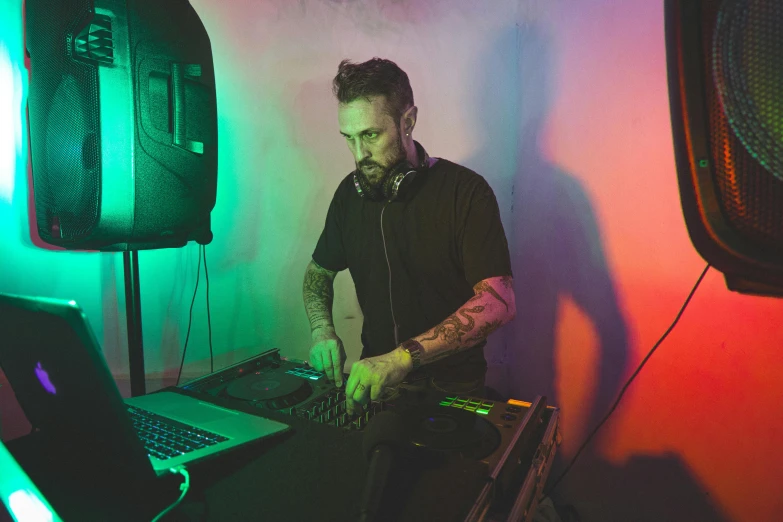 a dj in a black shirt working on his laptop