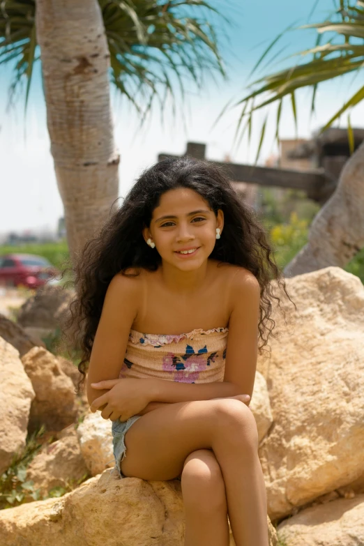 there is a young woman sitting on some rocks