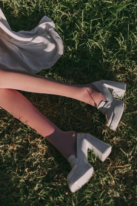 the woman is in white shoes sitting on grass