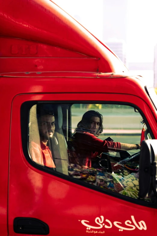 a man sits in his red pick - up truck