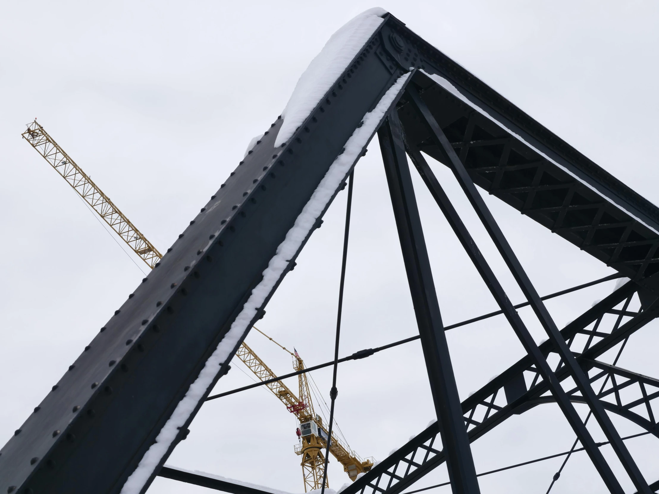 some construction cranes sitting over the top of a building