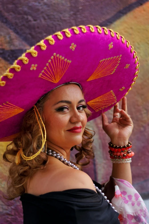 a girl in black and purple mexican attire wearing a pink sombrero