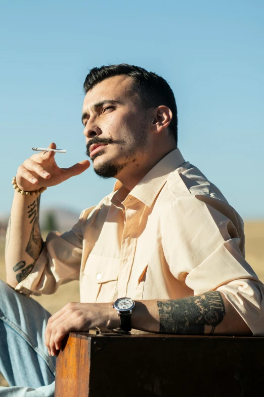 a man sitting in the shade smoking a cigarette