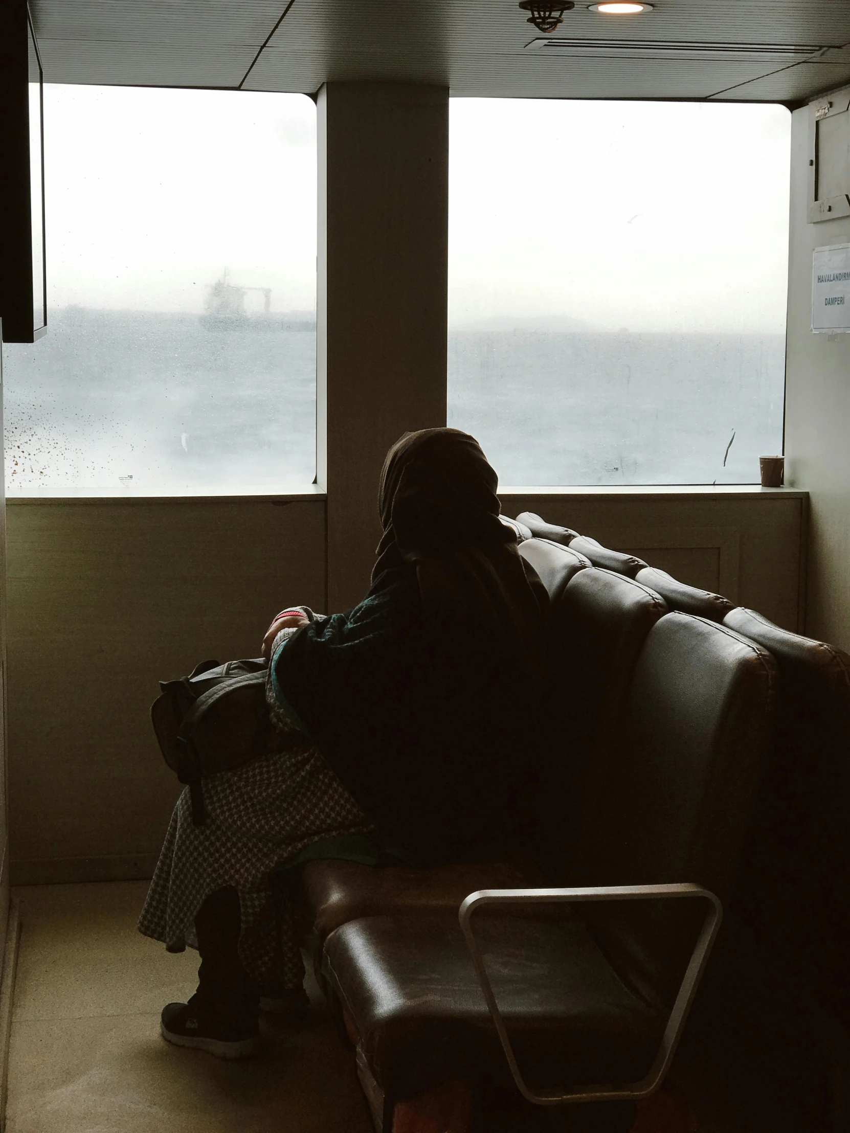 a person sitting alone in front of a window with suitcase