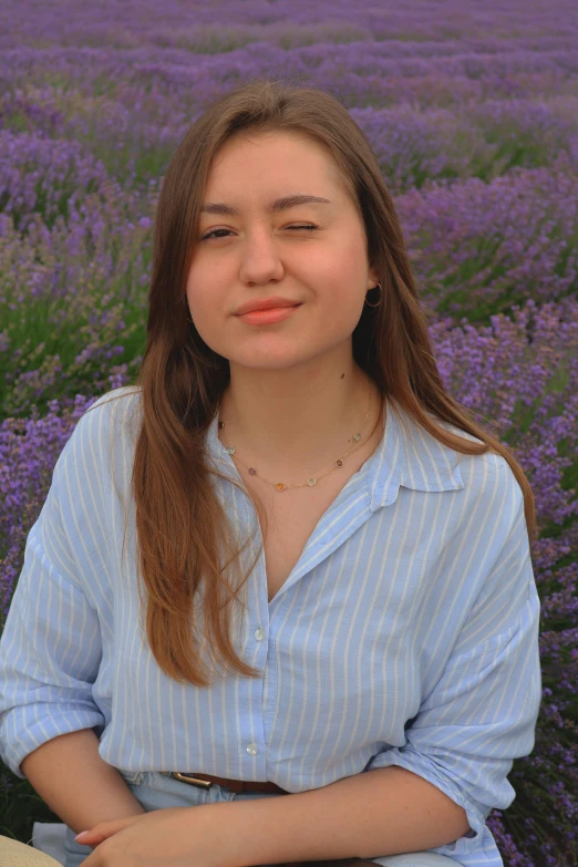 young woman in blue shirt standing next to lavender flowers