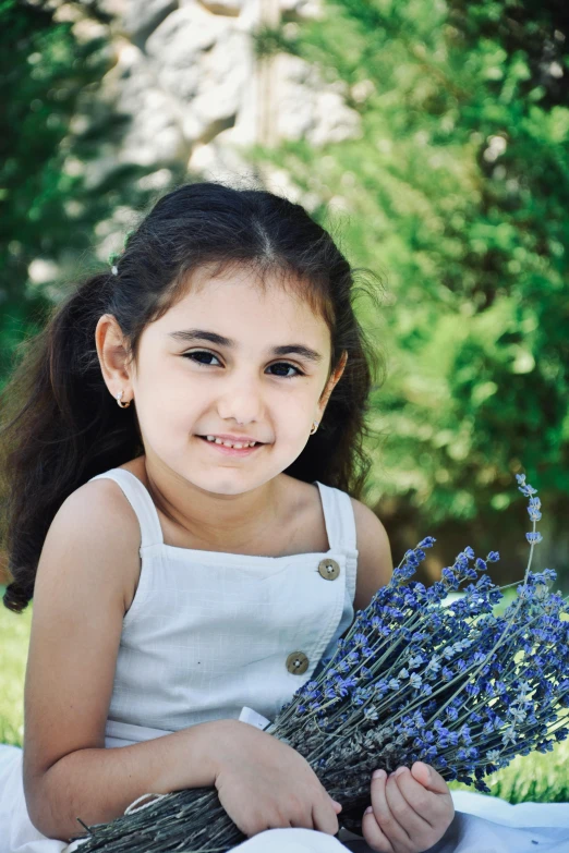 a little girl is holding a bunch of lavenders