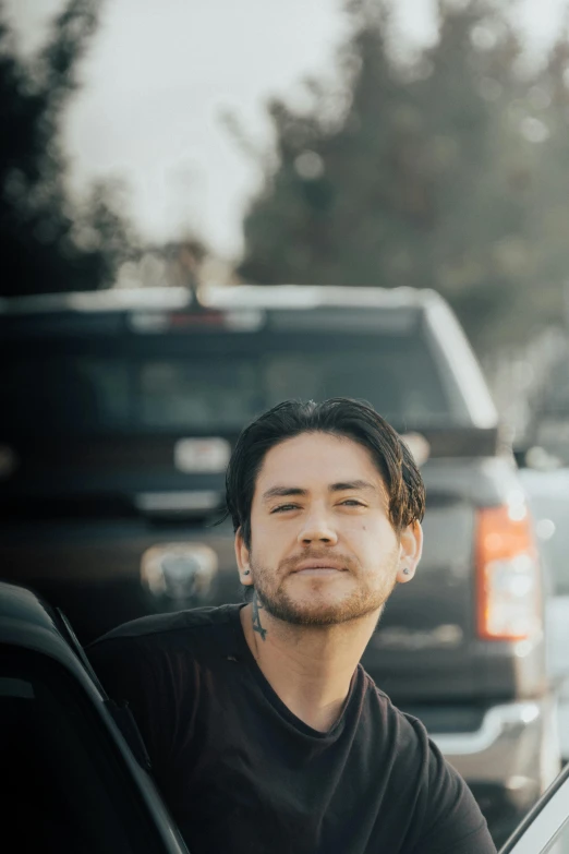 man sitting in car by the street in front of a truck