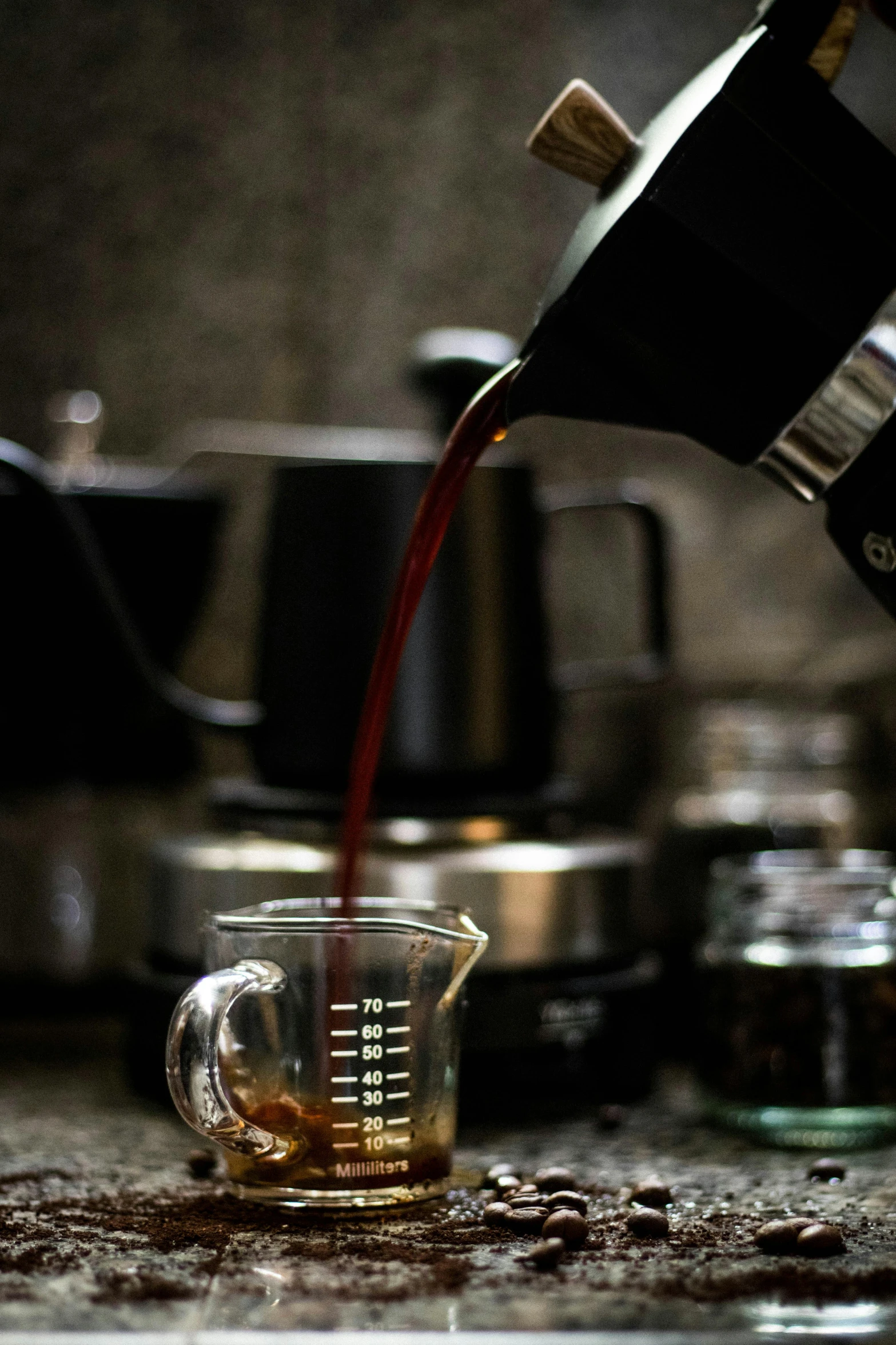 two cups filled with liquid are being poured onto a coffee pot