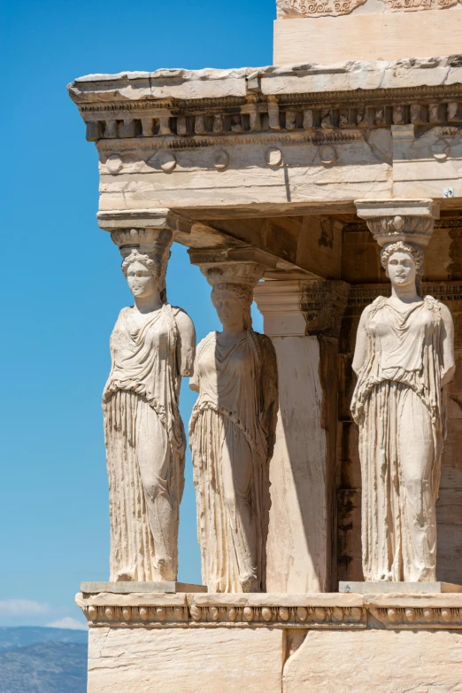 three large statues with some stone columns