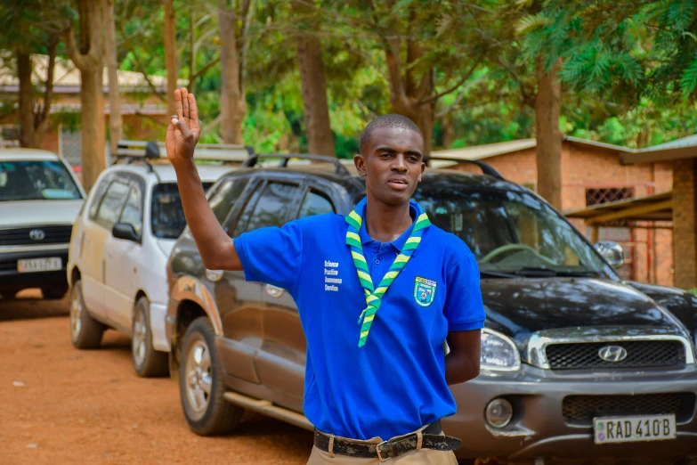 a man standing in front of cars waving at someone