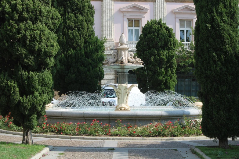 an ornate fountain with flowers in front of a building