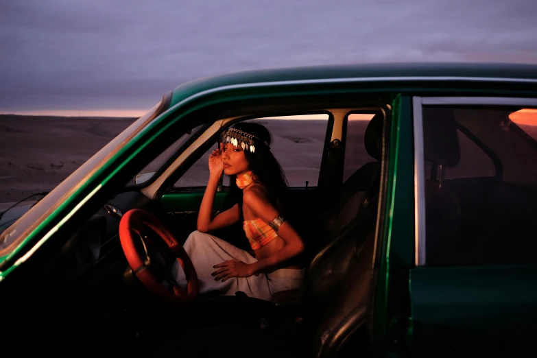 a woman driving a green car through a desert