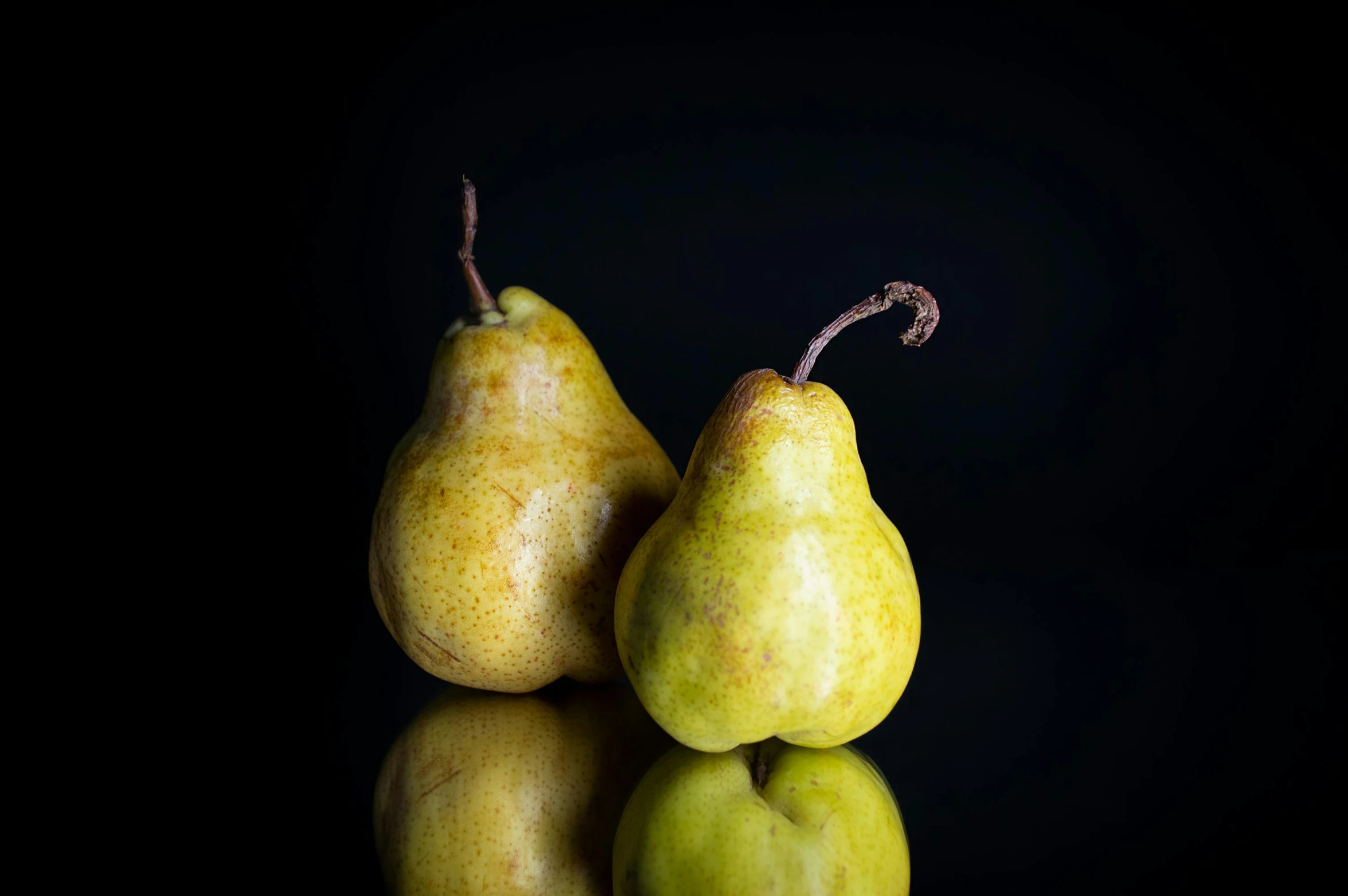 three pears in a row on reflective surface
