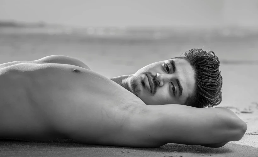 a man is laying on the sand and looking to his left