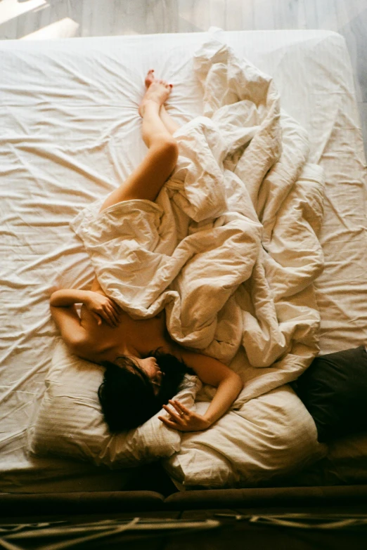 a couple cuddling underneath white sheets on a bed