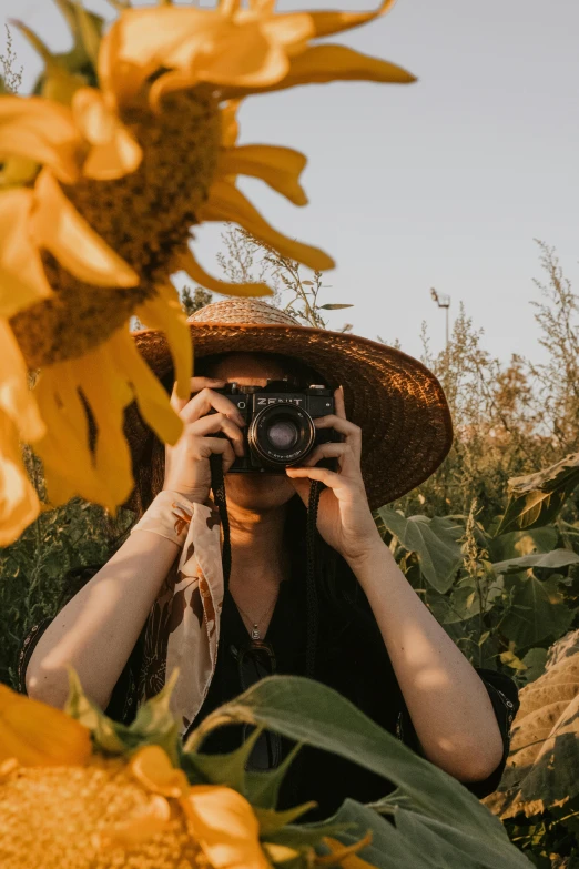 a woman wearing a brown hat taking pos with her camera