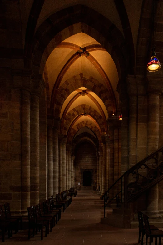 an empty hallway with two lamps and wooden benches