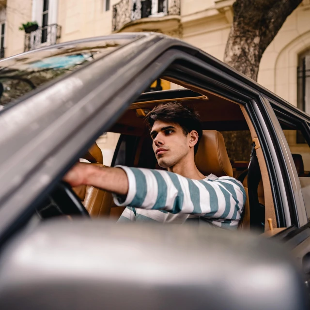 man sitting in a vehicle with a striped shirt on