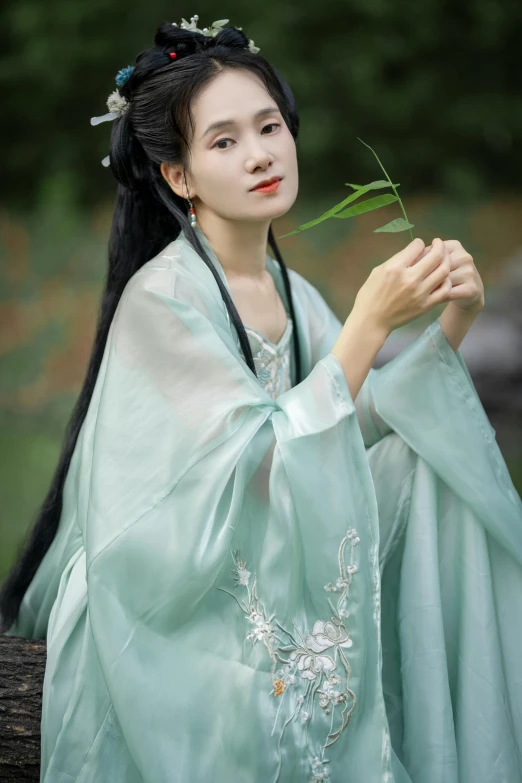 a woman in a traditional chinese outfit holding a green flower