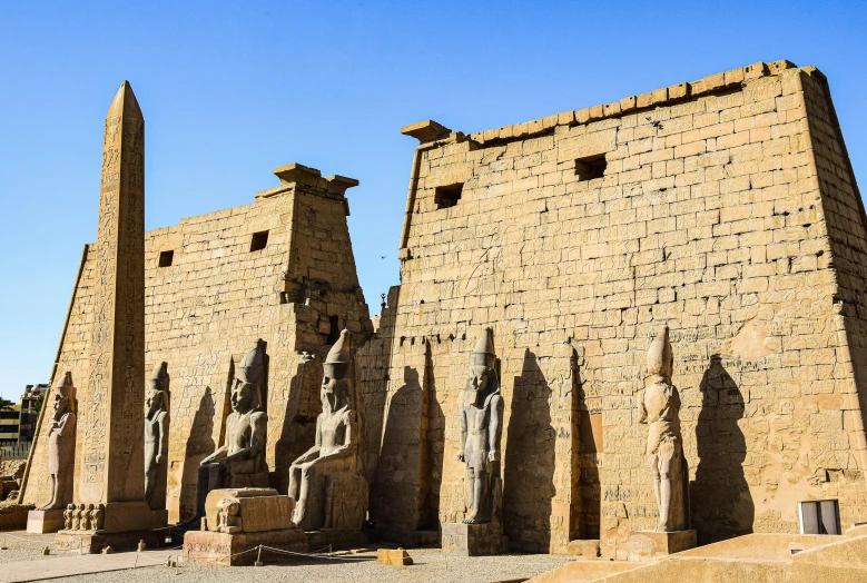 an ancient egyptian desert city, with statues of the pharaoh and the egyptian people