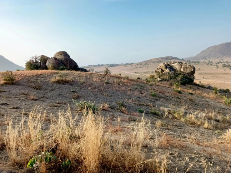 a couple of rocks sitting on top of a dry grass covered hill