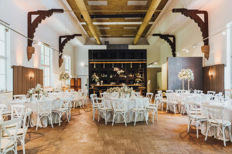 an elegant banquet hall with white tables, chandeliers and wooden ceilings